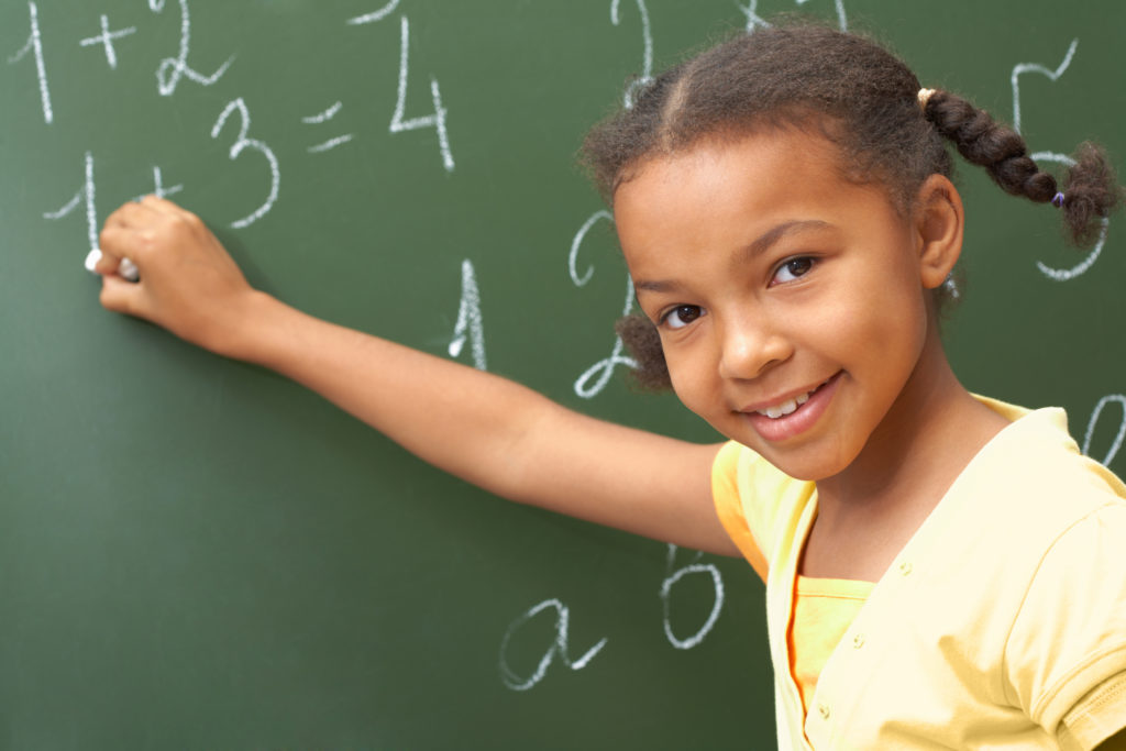 Girl answering math problems on the chalkboard.